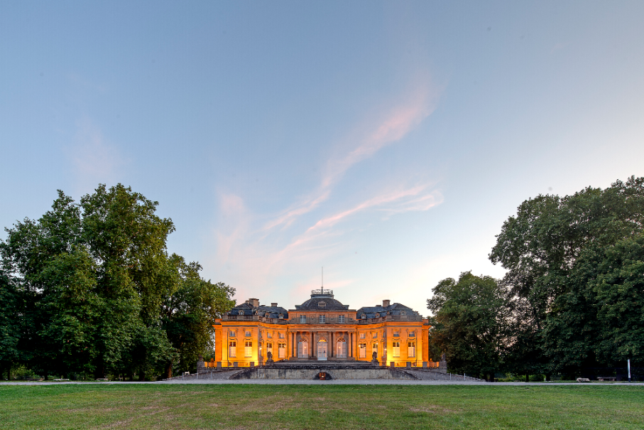 Das Seeschloss Monrepos leuchtet in warmem Licht bei Sonnenuntergang, umgeben von üppigen Bäumen und einem weiten Rasen., © Seeschloss Monrepos © Daniel Stauch Das Seeschloss Monrepos leuchtet in warmem Licht bei Sonnenuntergang, umgeben von üppigen Bäumen und einem weiten Rasen., © Seeschloss Monrepos © Daniel Stauch