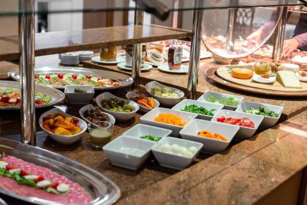 Ein reichhaltiges Frühstücksbuffet mit verschiedenen Schalen voller Gemüse, Obst und Aufschnitt auf einem Tresen., © Kronen Hotel GmbH Ein reichhaltiges Frühstücksbuffet mit verschiedenen Schalen voller Gemüse, Obst und Aufschnitt auf einem Tresen., © Kronen Hotel GmbH