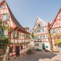 Fachwerkh&auml;user in Schorndorf mit roten Balken und gr&uuml;nen Fensterl&auml;den, umgeben von Pflanzen, unter blauem Himmel., &copy; Eigenbetrieb Tourismus und Citymanagement Schorndorf