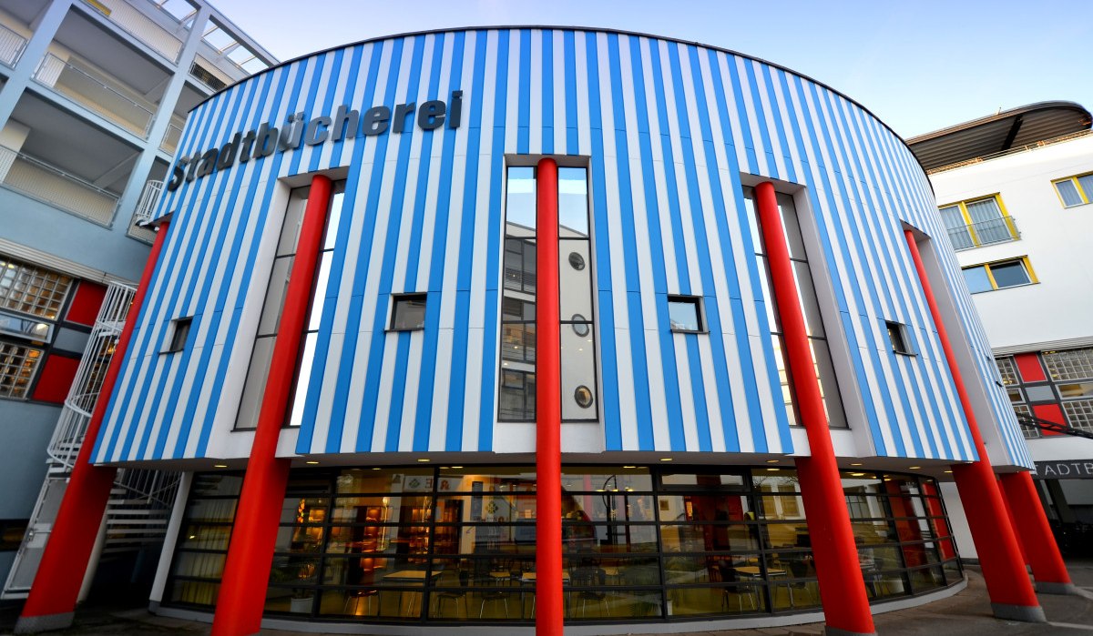 Die Stadtbücherei Fellbach zeigt eine Fassade mit blauen und weißen Streifen und roten Säulen. Moderne Architektur mit großen Fenstern., © Fellbach Tourismus Die Stadtbücherei Fellbach zeigt eine Fassade mit blauen und weißen Streifen und roten Säulen. Moderne Architektur mit großen Fenstern., © Fellbach Tourismus