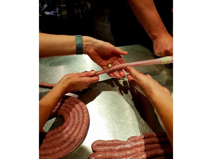 Hände von Personen füllen Wurstmasse in Därme auf einem Metalltisch. Die Szene findet in einem Kochkurs statt., © Kultweine-Kochwelten-Kunstücke - Kochschule Sonja Lenz Hände von Personen füllen Wurstmasse in Därme auf einem Metalltisch. Die Szene findet in einem Kochkurs statt., © Kultweine-Kochwelten-Kunstücke - Kochschule Sonja Lenz