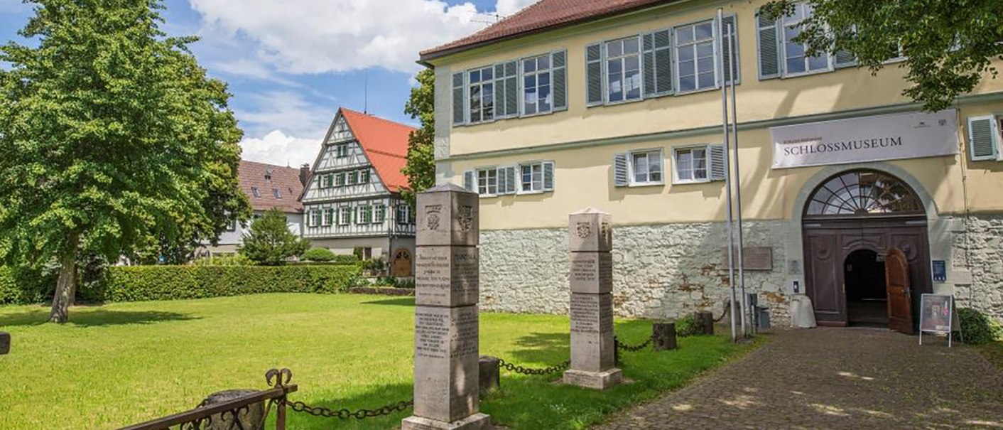 Eingang des Schlossmuseums in Kirchheim unter Teck, mit einem Fachwerkhaus im Hintergrund und einer grünen Wiese im Vordergrund., © Torsten Wenzler