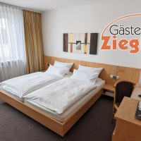Helles Hotelzimmer mit Doppelbett, Schreibtisch, Fernseher und Wasserkocher im G&auml;stehaus Ziegler. Moderne Dekoration und gro&szlig;e Fenster mit Vorh&auml;ngen., &copy; G&auml;stehaus Ziegler