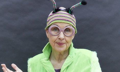 Eine Person tr&auml;gt ein gr&uuml;nes Kost&uuml;m mit einer bunten M&uuml;tze und Brille, die an ein Insekt erinnern. Der Hintergrund ist neutral., &copy; Reblaus F&uuml;hrung. Foto: Teamwerk