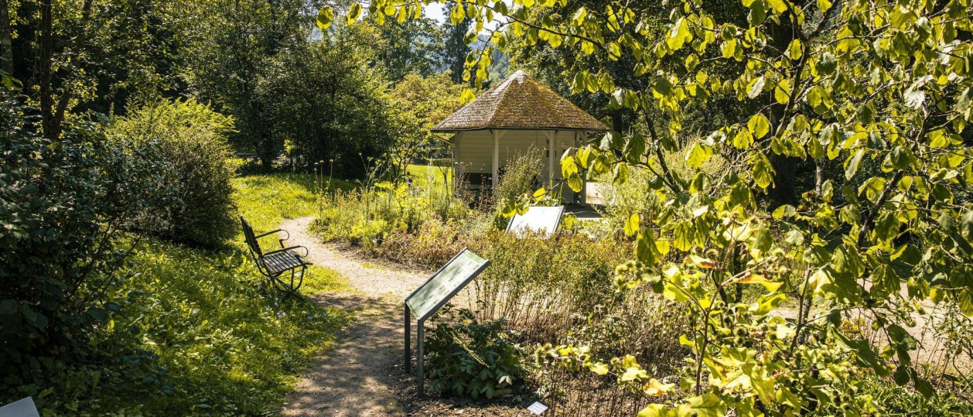 Ein grüner Garten mit Pavillon, Bank und Informationstafeln. Ein Weg schlängelt sich durch die üppige Vegetation. Sonniges Wetter., © Stuttgart-Marketing GmbH, Sarah Schmid