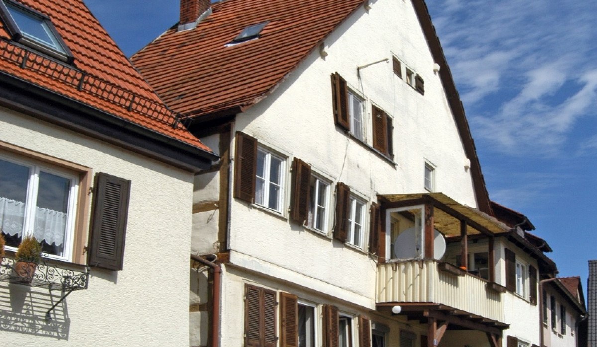 Traditionelles Fachwerkhaus mit rotem Ziegeldach, Holzfensterläden und kleinem Balkon. Ein rotes Auto steht davor, blauer Himmel im Hintergrund., © Natur.Nah. Schönbuch & Heckengäu Traditionelles Fachwerkhaus mit rotem Ziegeldach, Holzfensterläden und kleinem Balkon. Ein rotes Auto steht davor, blauer Himmel im Hintergrund., © Natur.Nah. Schönbuch & Heckengäu