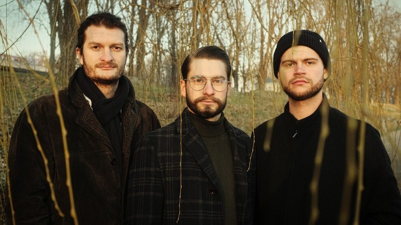 Drei Männer in Winterkleidung stehen in einem kahlen Wald und blicken ernst in die Kamera., © Interessengemeinschaft Kultur Sindelfingen / Böblingen e.V.