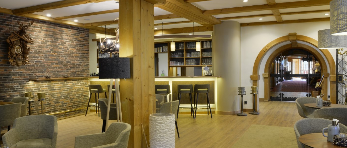 Gemütliche Hotelbar mit Holzbalken, Backsteinwand, modernen Möbeln und einem großen Torbogen im Hintergrund., © TOMAS