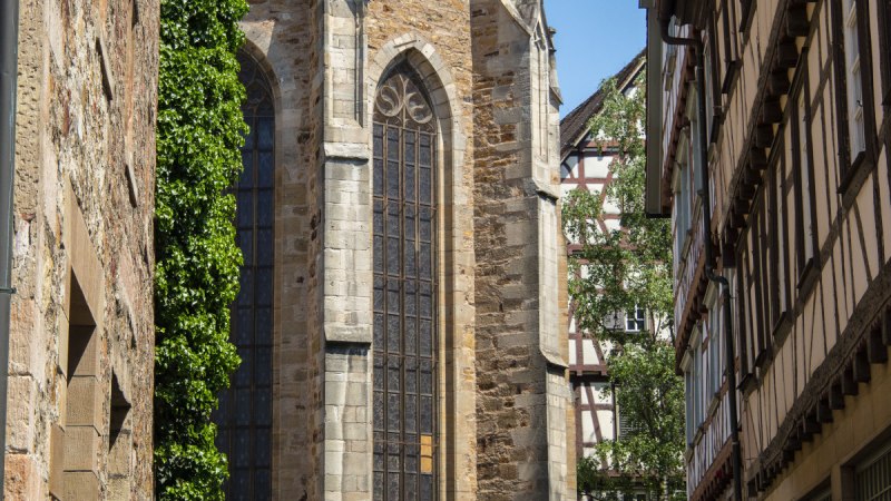 Gotische Martinskirche mit hohen Fenstern, umgeben von Fachwerkh&auml;usern und einem Stra&szlig;enschild im Vordergrund. Sonniger Tag, blauer Himmel., &copy; Stadt Kirchheim unter Teck