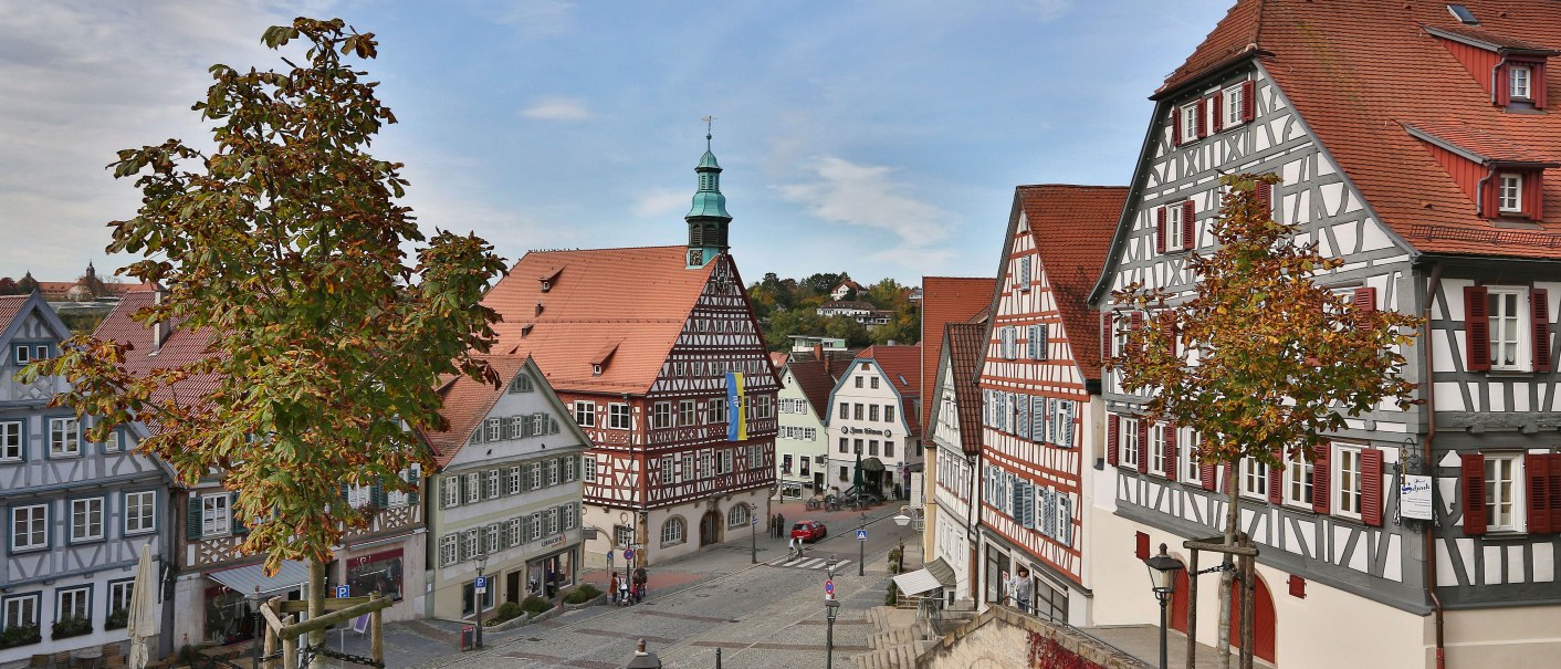 Der Marktplatz in Backnang zeigt malerische Fachwerkhäuser und einen gepflasterten Platz. Im Hintergrund ist ein Turm mit grünem Dach zu sehen., © Edgar Layher Fotografie