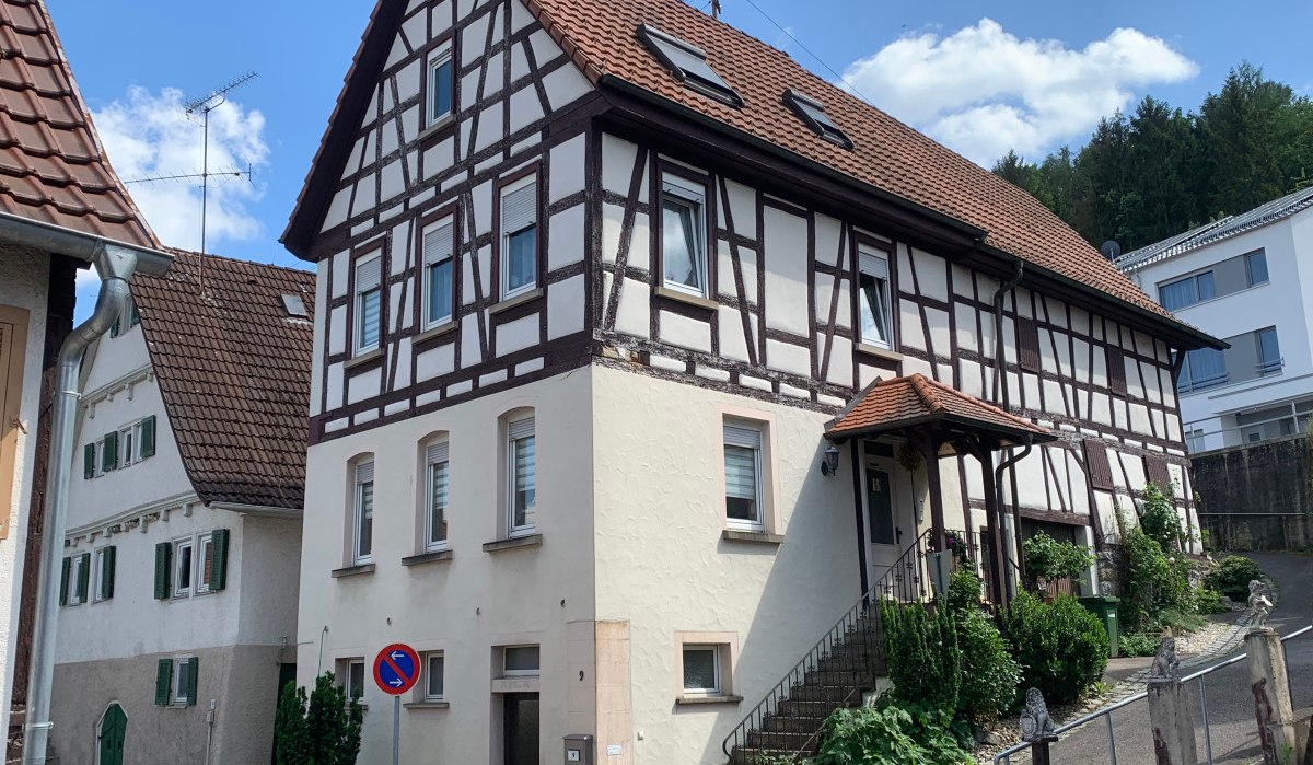 Fachwerkhaus mit rotem Dach und Eingangstreppe. Es steht in einer Wohngegend mit weiteren Häusern und einem blauen Himmel im Hintergrund., © Land der 1000 Hügel - Kraichgau-Stromberg Fachwerkhaus mit rotem Dach und Eingangstreppe. Es steht in einer Wohngegend mit weiteren Häusern und einem blauen Himmel im Hintergrund., © Land der 1000 Hügel - Kraichgau-Stromberg