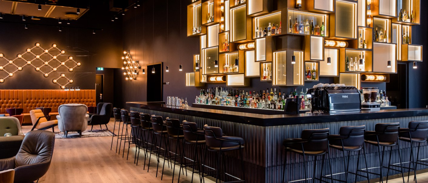 Elegante Bar mit stilvoller Beleuchtung, modernen Sitzgelegenheiten und einer gut bestückten Theke in einem schicken Ambiente., © TOMAS Elegante Bar mit stilvoller Beleuchtung, modernen Sitzgelegenheiten und einer gut bestückten Theke in einem schicken Ambiente., © TOMAS