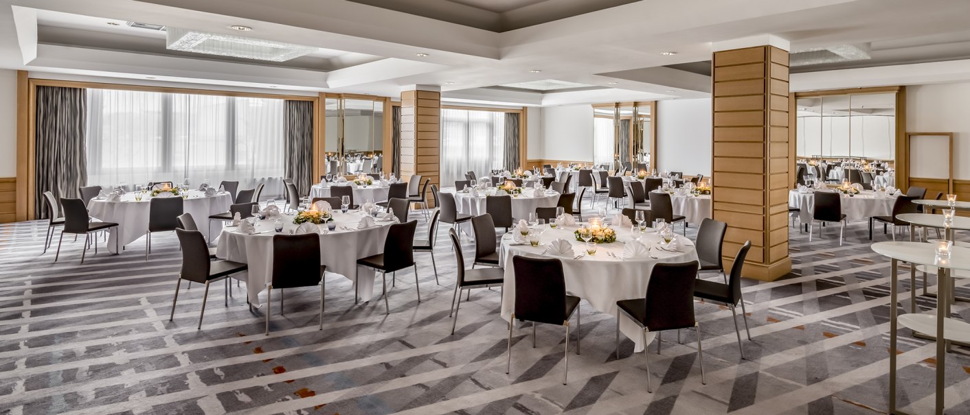 Eleganter Ballsaal mit runden Tischen, weißen Tischdecken und Blumenarrangements, bereit für eine Veranstaltung., © Stuttgart Marriott Hotel Sindelfingen