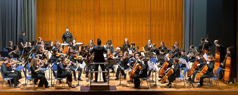 Ein Orchester mit Streich- und Blasinstrumenten spielt auf einer B&uuml;hne. Der Dirigent steht im Vordergrund, w&auml;hrend die Musiker konzentriert ihre Instrumente spielen., &copy; Stadtverwaltung Kirchheim unter Teck - Kulturring