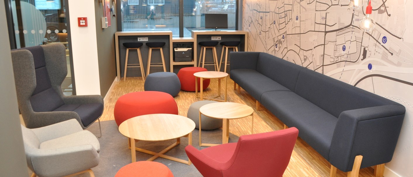 Moderne Lobby im Holiday Inn Express Sindelfingen mit bunten Sesseln, Hockern und Tischen. Eine große Wandkarte und Hängelampen schmücken den Raum., © tristar GmbH Moderne Lobby im Holiday Inn Express Sindelfingen mit bunten Sesseln, Hockern und Tischen. Eine große Wandkarte und Hängelampen schmücken den Raum., © tristar GmbH