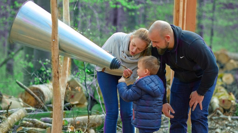 Eine Familie mit einem Kind untersucht einen großen Hörtrichter im Wald auf dem Herzog-Jäger-Pfad., © Natur.Nah. Schönbuch & Heckengäu