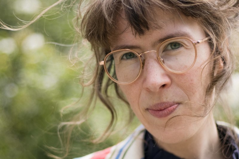 Nahaufnahme einer Frau mit Brille und lockigem Haar vor unscharfem, grünem Hintergrund., © Kulturamt der Stadt Esslingen am Neckar