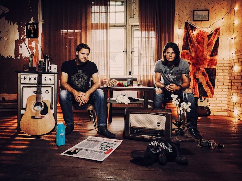 Zwei Männer sitzen in einem gemütlichen Raum mit Gitarre, Radio und britischer Flagge. Der Raum ist mit Lichterketten dekoriert., © Kulturfenster Bönnigheim e. V. Zwei Männer sitzen in einem gemütlichen Raum mit Gitarre, Radio und britischer Flagge. Der Raum ist mit Lichterketten dekoriert., © Kulturfenster Bönnigheim e. V.