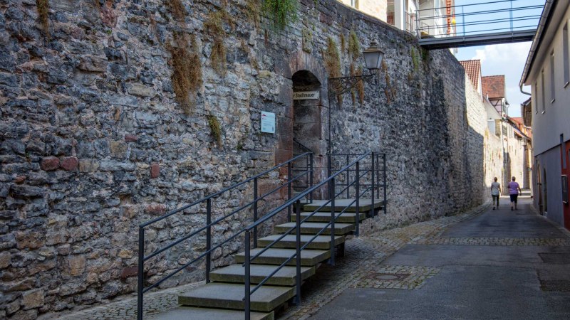 Alte Stadtmauer mit Treppe, Laterne und zwei Personen in einer engen Gasse. Eine Brücke verbindet Gebäude über der Mauer., © Stuttgart-Marketing GmbH, Foto: Achim Mende Alte Stadtmauer mit Treppe, Laterne und zwei Personen in einer engen Gasse. Eine Brücke verbindet Gebäude über der Mauer., © Stuttgart-Marketing GmbH, Foto: Achim Mende