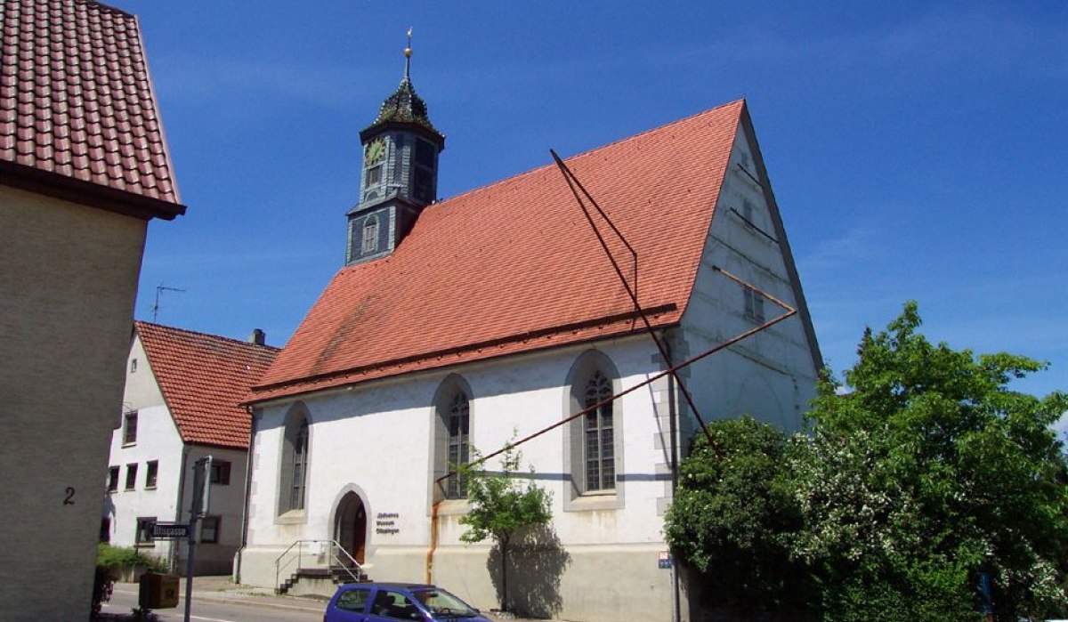 Ein historisches Gebäude mit rotem Ziegeldach und Turm, beschriftet als Jüdisches Museum. Ein Auto parkt davor, blauer Himmel im Hintergrund., © Landkreis Göppingen Ein historisches Gebäude mit rotem Ziegeldach und Turm, beschriftet als Jüdisches Museum. Ein Auto parkt davor, blauer Himmel im Hintergrund., © Landkreis Göppingen