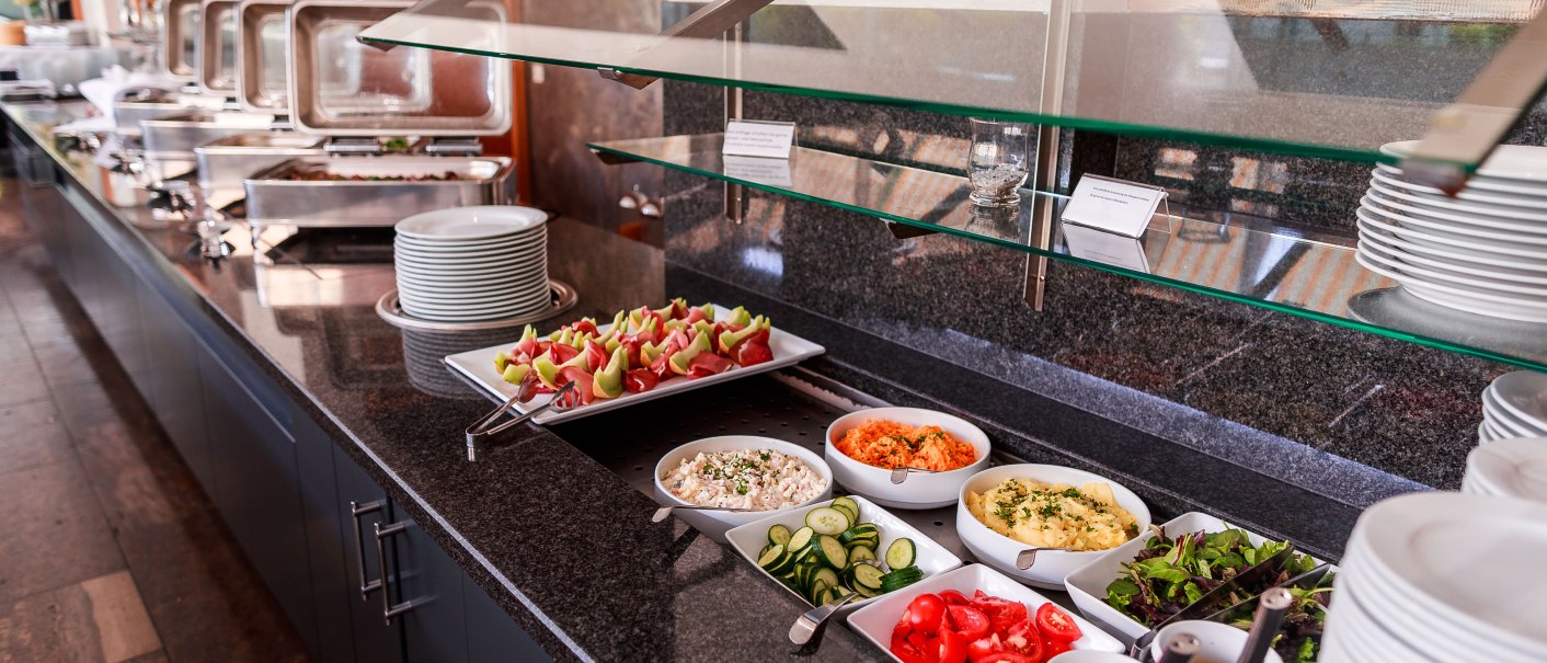 Ein Buffet in einem Restaurant mit verschiedenen Speisen wie Salaten, Aufschnitt und warmen Gerichten. Teller und Besteck sind bereitgestellt., © Plaza Residence Stuttgart-Ditzingen Ein Buffet in einem Restaurant mit verschiedenen Speisen wie Salaten, Aufschnitt und warmen Gerichten. Teller und Besteck sind bereitgestellt., © Plaza Residence Stuttgart-Ditzingen