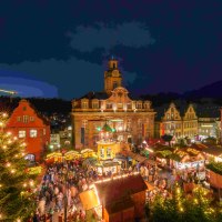 Beleuchtete Weihnachtspyramide und geschmückter Baum auf dem Weihnachtsmarkt in Schwäbisch Hall, umgeben von Menschen in festlicher Stimmung., © Michael Kühneisen