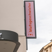 Ein Geschäftsschild mit der Aufschrift 'blutsgeschwister' an einem Gebäude. Ein weiteres Schild zeigt das Logo mit Herz und Anker., © Stuttgart-Marketing GmbH, Sarah Schmid Ein Geschäftsschild mit der Aufschrift 'blutsgeschwister' an einem Gebäude. Ein weiteres Schild zeigt das Logo mit Herz und Anker., © Stuttgart-Marketing GmbH, Sarah Schmid