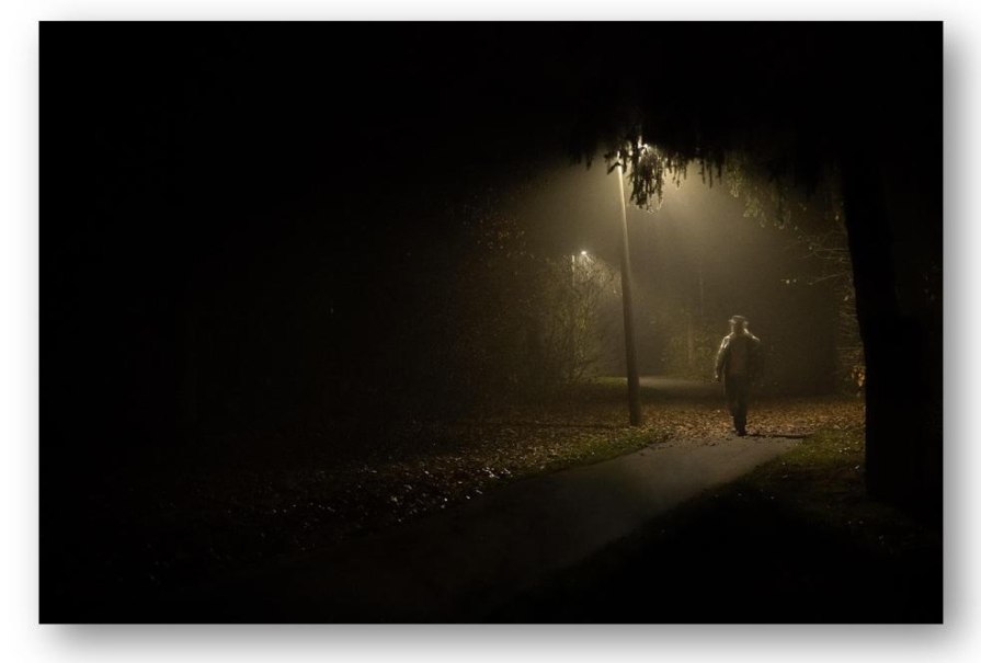 Eine Person spaziert nachts auf einem beleuchteten Weg durch einen nebligen Park. Die Umgebung ist dunkel, nur die Laternen spenden Licht., &copy; pixabay