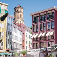 Bunte Geb&auml;ude und Marktst&auml;nde auf einem Marktplatz, mit einem Kirchturm im Hintergrund unter blauem Himmel., &copy; SMG, trickytine