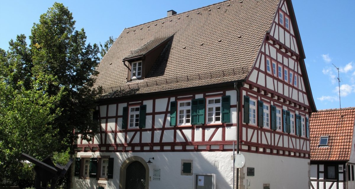 Fachwerkhaus mit grün-weißen Fensterläden und Satteldach, umgeben von Bäumen und blauem Himmel., © Natur.Nah. Schönbuch & Heckengäu Fachwerkhaus mit grün-weißen Fensterläden und Satteldach, umgeben von Bäumen und blauem Himmel., © Natur.Nah. Schönbuch & Heckengäu
