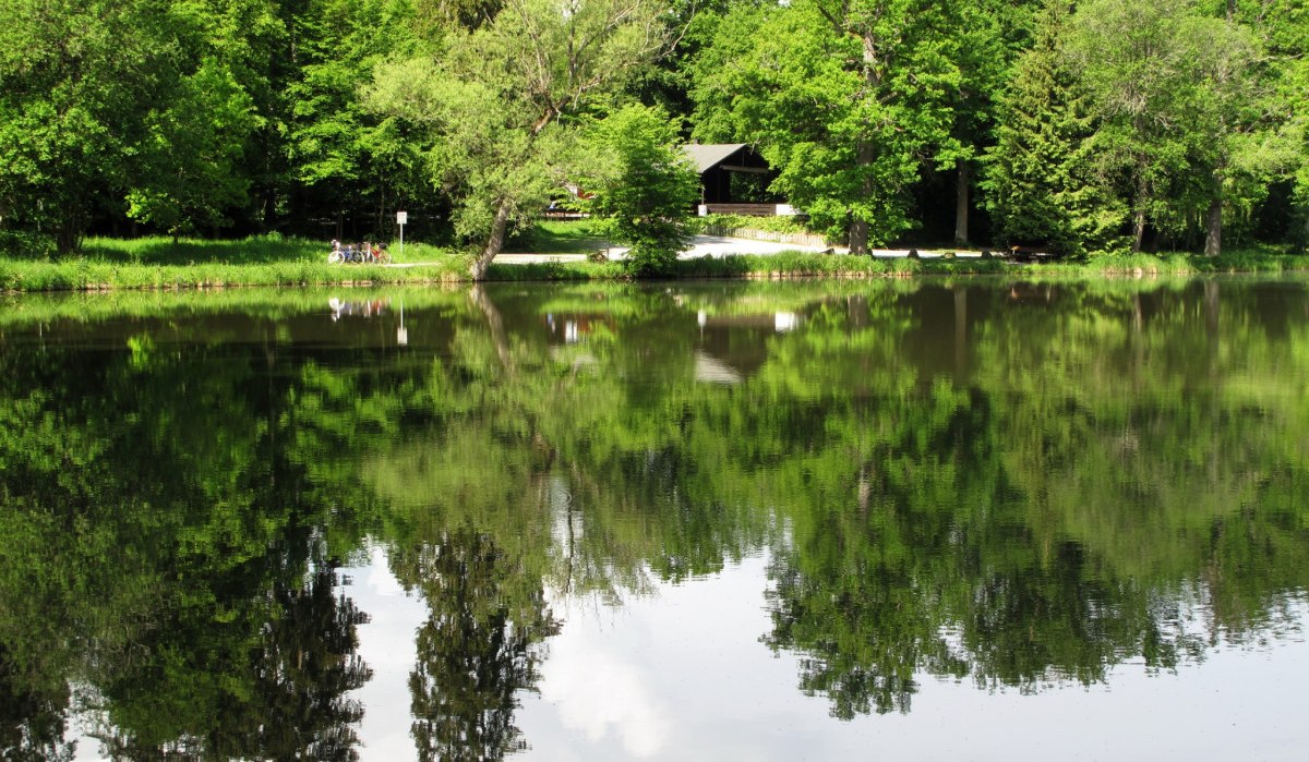 Ein idyllischer See mit klarer Spiegelung der umliegenden B&auml;ume. Ein Pavillon und Fahrr&auml;der sind am Ufer sichtbar., &copy; RadL Leonberg