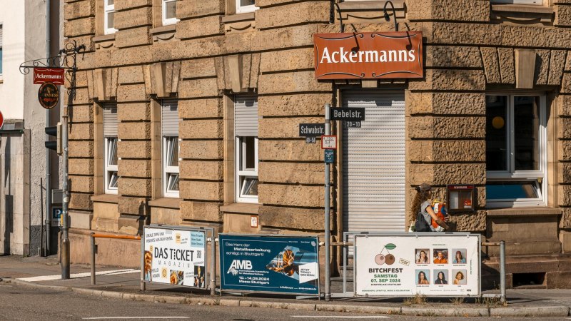 Eckgebäude mit dem Schild 'Ackermanns' an der Fassade. Straßenschilder für Bebelstr. und Schwabstr. sind sichtbar, ebenso mehrere Werbeplakate., © SMG, Sarah Schmid Eckgebäude mit dem Schild 'Ackermanns' an der Fassade. Straßenschilder für Bebelstr. und Schwabstr. sind sichtbar, ebenso mehrere Werbeplakate., © SMG, Sarah Schmid
