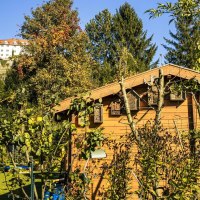 Ein Garten mit einer Holzhütte im Vordergrund, umgeben von Bäumen und Pflanzen. Im Hintergrund ist ein Schloss auf einem Hügel zu sehen., © Stuttgart Marketing GmbH, Sarah Schmid Ein Garten mit einer Holzhütte im Vordergrund, umgeben von Bäumen und Pflanzen. Im Hintergrund ist ein Schloss auf einem Hügel zu sehen., © Stuttgart Marketing GmbH, Sarah Schmid