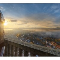 Blick von einem Balkon auf eine nebelverhangene Stadt im Morgenlicht. Die Sonne geht am Horizont auf und taucht die Szene in warmes Licht., &copy; Stadt N&uuml;rtingen