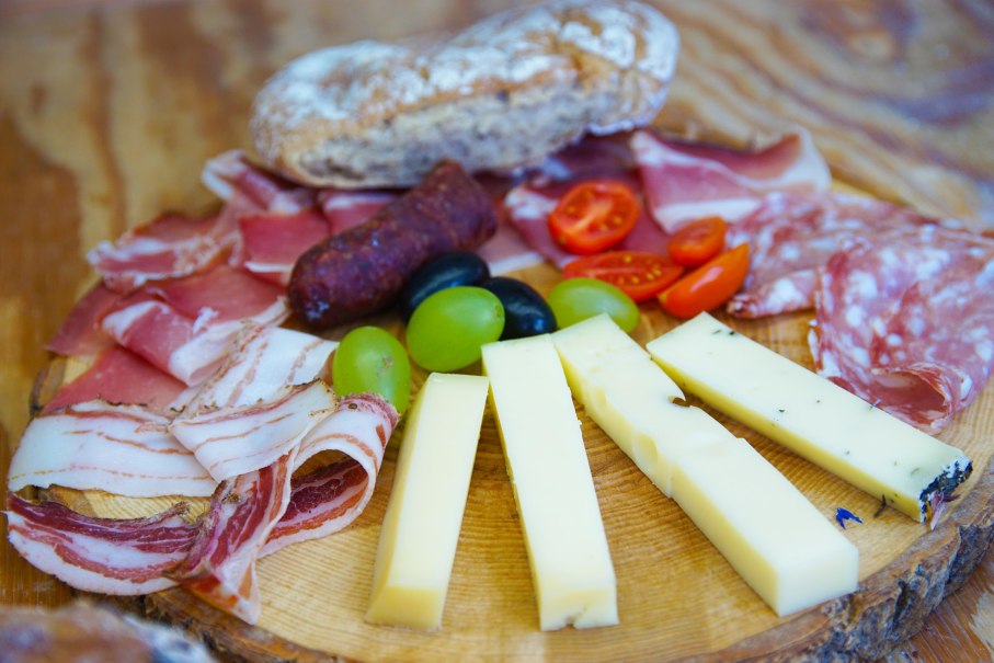 Ein Südtiroler Teller mit verschiedenen Wurstsorten, Käsestreifen, Brot, Trauben und Tomaten auf einem Holzbrett., © T.Krytzner