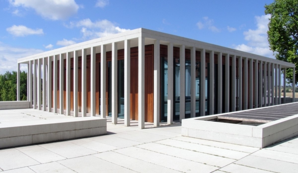 Modernes Gebäude mit Glasfassade und weißen Säulen, umgeben von einer gepflasterten Fläche. Der Himmel ist blau mit einigen Wolken., © Schillerstadt Marbach Modernes Gebäude mit Glasfassade und weißen Säulen, umgeben von einer gepflasterten Fläche. Der Himmel ist blau mit einigen Wolken., © Schillerstadt Marbach