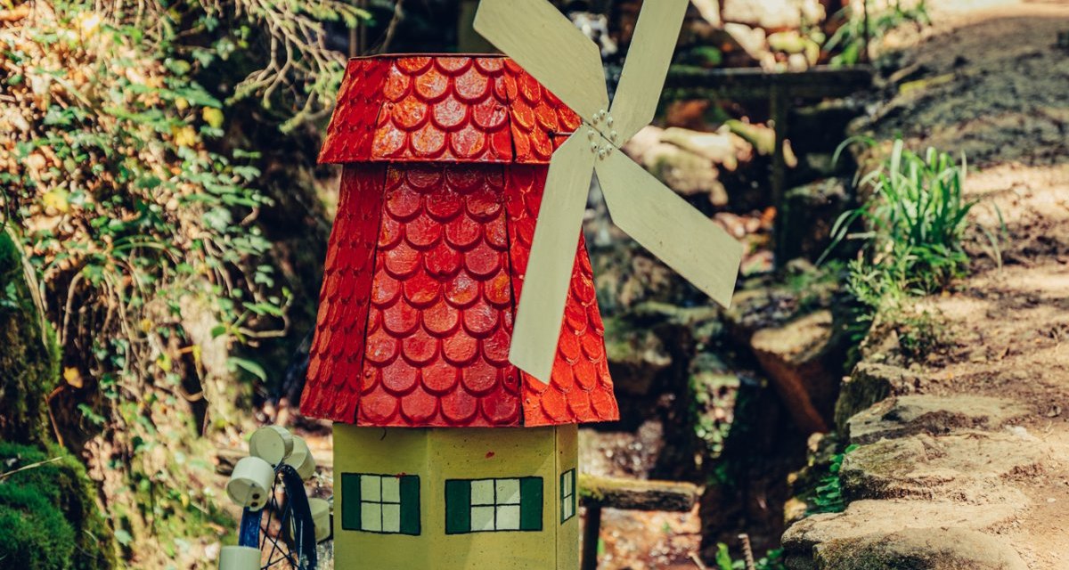 Eine kleine, bunte Mühle mit rotem Dach und Wasserrad steht im Wald neben einem Pfad. Im Hintergrund sind Bäume und Spaziergänger zu sehen., © Tourismus Ostalb Eine kleine, bunte Mühle mit rotem Dach und Wasserrad steht im Wald neben einem Pfad. Im Hintergrund sind Bäume und Spaziergänger zu sehen., © Tourismus Ostalb