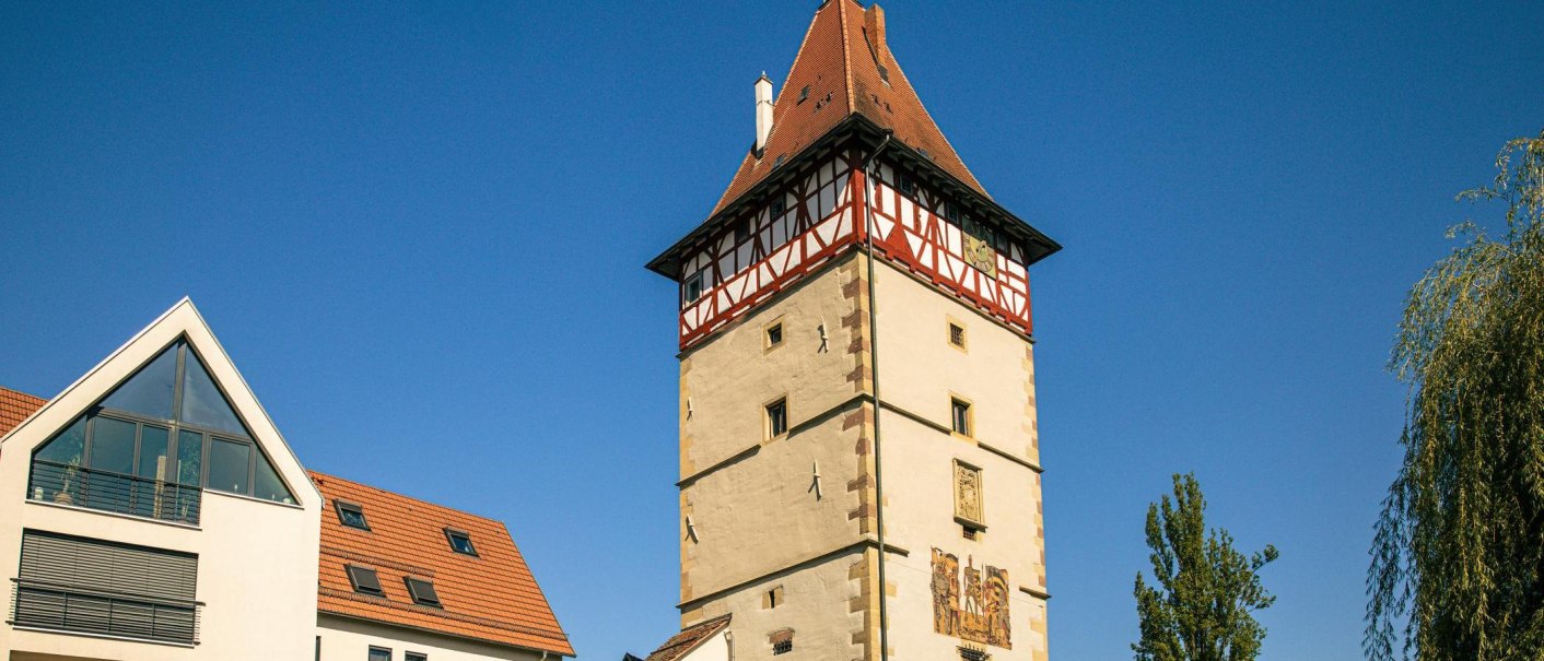 Das Beinsteiner Tor in Waiblingen, ein historischer Turm mit Fachwerk und rotem Dach, steht neben modernen Gebäuden unter klarem, blauem Himmel., © Stuttgart-Marketing GmbH, Sarah Schmid Das Beinsteiner Tor in Waiblingen, ein historischer Turm mit Fachwerk und rotem Dach, steht neben modernen Gebäuden unter klarem, blauem Himmel., © Stuttgart-Marketing GmbH, Sarah Schmid