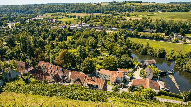 Blick auf Vaihingen an der Enz mit Schloss Kaltenstein, umgeben von gr&uuml;nen W&auml;ldern und Feldern. Im Vordergrund sind H&auml;user und ein Fluss zu sehen., &copy; Stuttgart-Marketing GmbH, Sarah Schmid