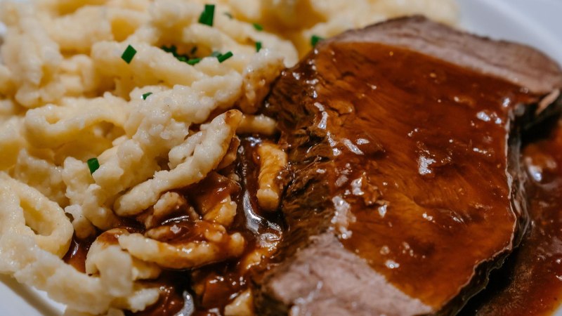 Ein Teller mit saftigem Braten in dunkler Soße, serviert mit Spätzle, garniert mit Schnittlauch., © SMG, Thomas Niedermüller
