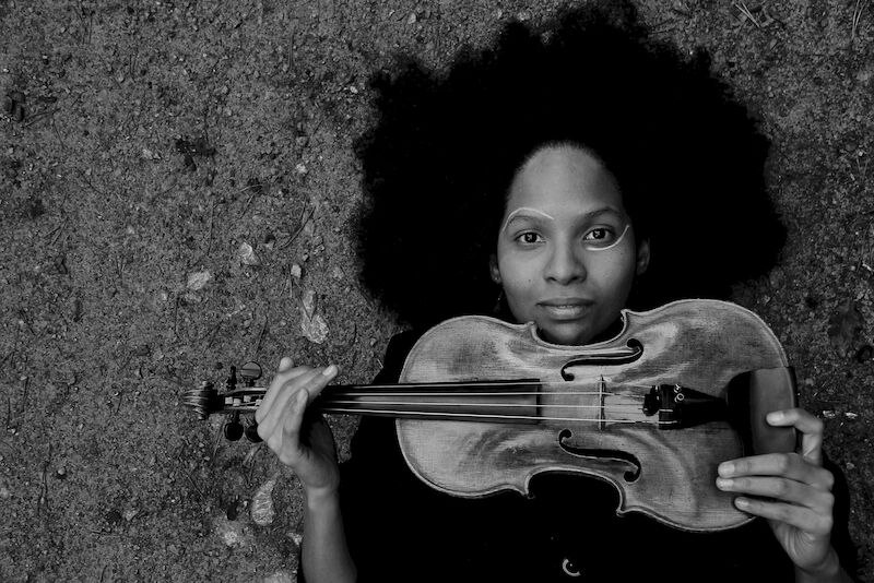 Person mit Afrofrisur liegt auf dem Boden und hält eine Geige. Schwarz-weiß Fotografie mit märchenhaftem Titel., © Stadt Sindelfingen