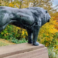 Bronzestatue eines Löwen auf einem Sockel, umgeben von buntem Herbstlaub und Blick auf eine weite Landschaft., © SMG, Martina Denker Bronzestatue eines Löwen auf einem Sockel, umgeben von buntem Herbstlaub und Blick auf eine weite Landschaft., © SMG, Martina Denker