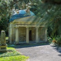 Ein altes Mausoleum mit S&auml;ulen und Kuppel auf einem Friedhof, umgeben von B&auml;umen und Grabsteinen. Die Sonne scheint durch die &Auml;ste., &copy; &copy; T&E, Benjamin Stollenberg