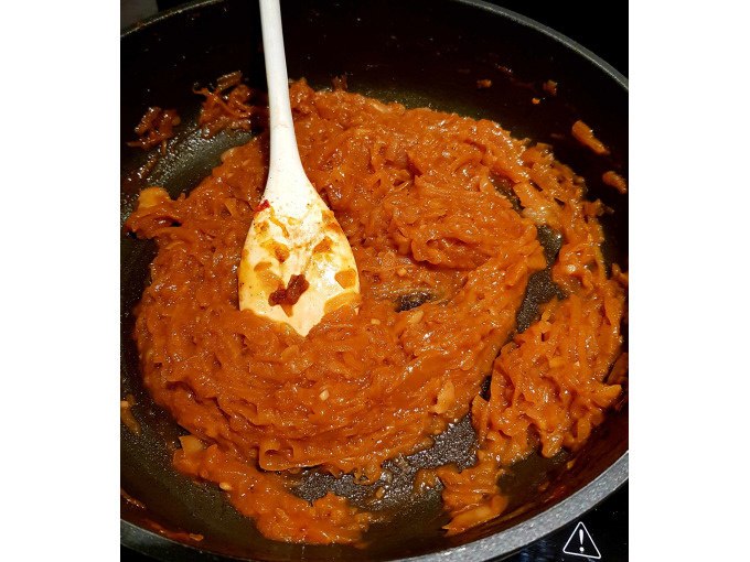 Eine rote Sauce wird in einer Pfanne mit einem wei&szlig;en Holzl&ouml;ffel ger&uuml;hrt., &copy; Kultweine-Kochwelten-Kunst&uuml;cke - Kochschule Sonja Lenz