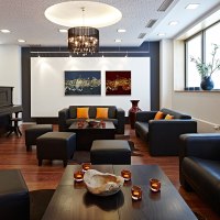 Elegante Lounge mit schwarzen Sofas, orangefarbenen Kissen, Klavier, Kunstwerken und Kerzen auf Holztischen., © Studierendenwerk Stuttgart Elegante Lounge mit schwarzen Sofas, orangefarbenen Kissen, Klavier, Kunstwerken und Kerzen auf Holztischen., © Studierendenwerk Stuttgart