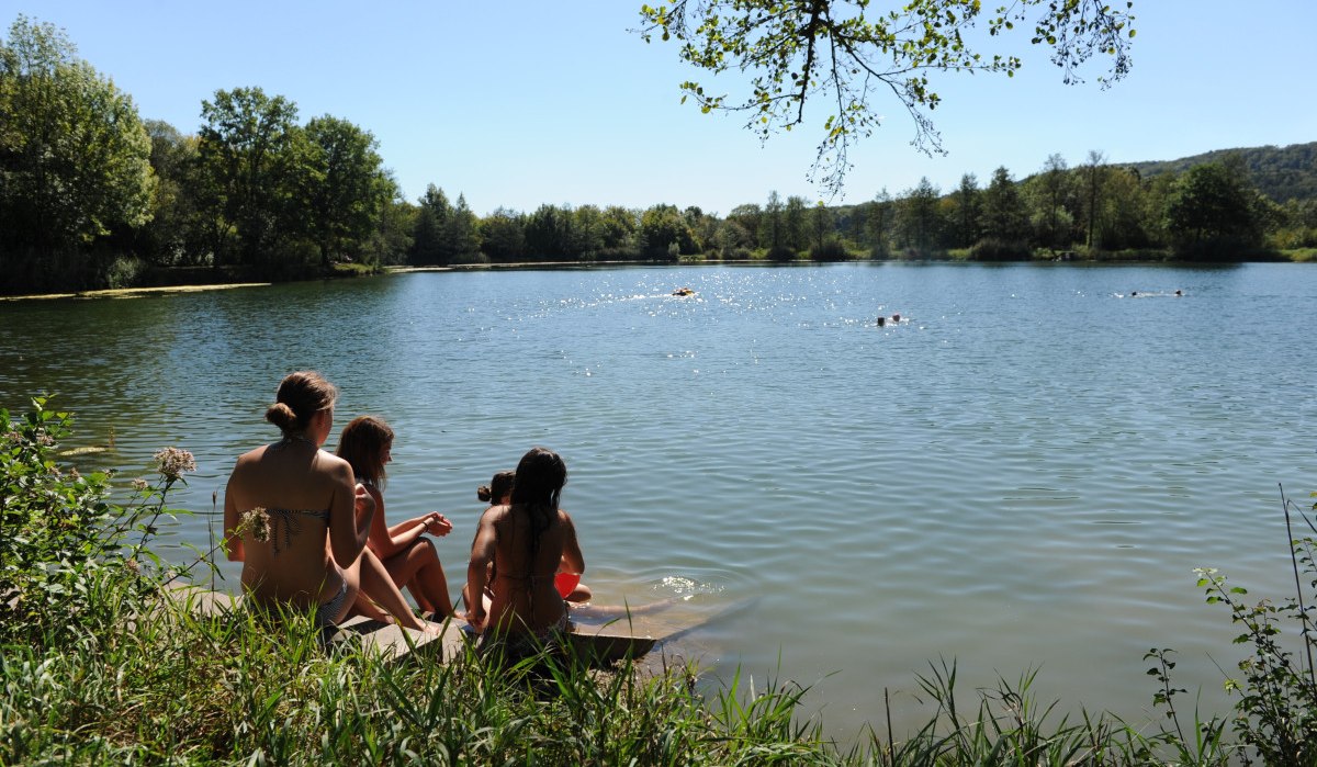 Menschen sitzen am Ufer eines Sees, genießen die Sonne und beobachten Schwimmer im Wasser. Umgeben von grüner Natur und klarem Himmel., © Land der 1000 Hügel - Kraichgau-Stromberg Menschen sitzen am Ufer eines Sees, genießen die Sonne und beobachten Schwimmer im Wasser. Umgeben von grüner Natur und klarem Himmel., © Land der 1000 Hügel - Kraichgau-Stromberg