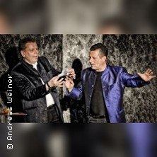 Zwei M&auml;nner in eleganter Kleidung f&uuml;hren eine Zaubershow auf. Einer h&auml;lt ein Kartenspiel, w&auml;hrend der andere eine Geste macht., &copy; links im Bild