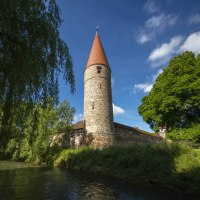 Ein mittelalterlicher Turm mit rotem Dach steht malerisch neben einem Fluss, umgeben von &uuml;ppigem Gr&uuml;n und einer alten Steinmauer., &copy; Stadtverwaltung Weil der Stadt