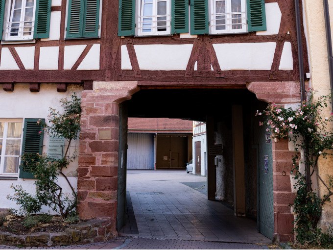 Ein Fachwerkhaus mit gr&uuml;n gestrichenen Fensterl&auml;den und einem Torbogen, der zu einem Innenhof f&uuml;hrt. Kletterrosen schm&uuml;cken die Fassade., &copy; Stadtverwaltung Weil der Stadt
