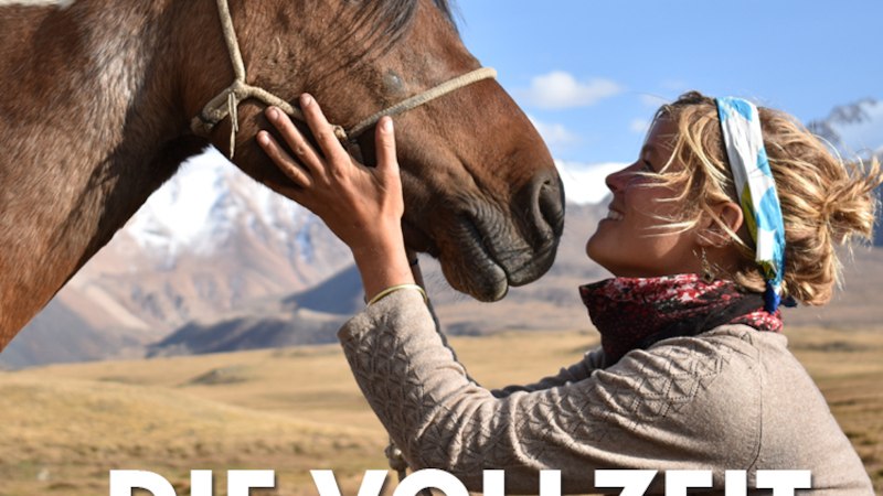 Eine Frau mit Kopftuch streichelt ein Pferd in einer weiten, bergigen Landschaft. Der Himmel ist blau und klar. Text: "DIE VOLLZEIT ABENTEURERIN"., © Expedition Erde